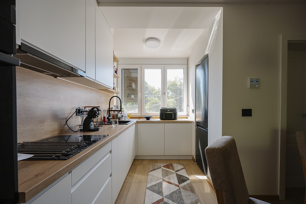 Cocina en L de frentes blancos con encimera de madera